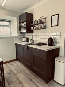 a kitchen with brown cabinets and a counter top at Ben Nevis Inn Rooms in Fort William