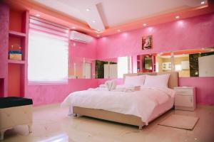 a pink bedroom with a bed and a large mirror at LUX apartman savić in Aleksinac