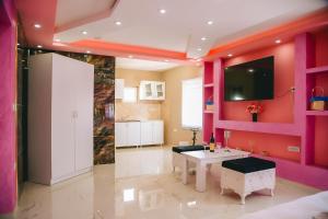 a kitchen with pink walls and a table and a tv at LUX apartman savić in Aleksinac