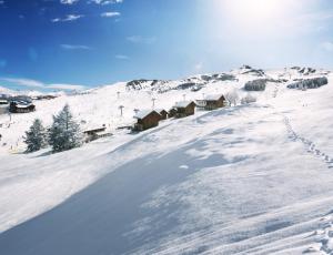 a snow covered slope with houses on a mountain at TERRESENS Le Caprice Blanc in La Toussuire