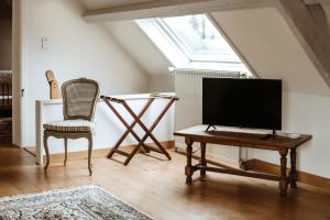 a living room with a tv and a chair and a table at Haras de Baudemont in Ittre