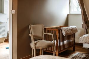 a chair and a crib in a room at Haras de Baudemont in Ittre