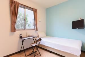 a bedroom with a bed and a desk and a window at Rich Reson Ishigaki in Ishigaki Island