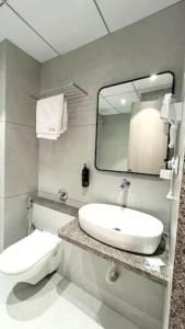 a bathroom with a sink and a toilet and a mirror at Hotel Unicorn Althan, Surat in Surat +20 photos