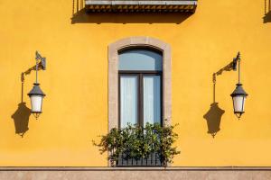 a yellow building with two lights and a window at Hotel Bremon by Grup Duquessa in Cardona