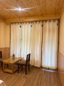 a living room with a table and white curtains at The Zoland in Jibhi +29 photos