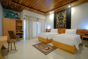 a bedroom with two beds and a desk in it at Giri Rose Boutique Hotel in Kuta Lombok +30 photos