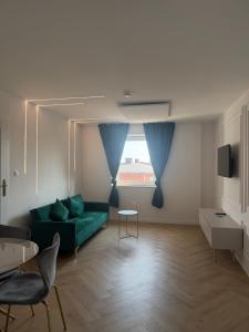 a living room with a green couch and a window at Brickller Apartments by Letrent in Żyrardów