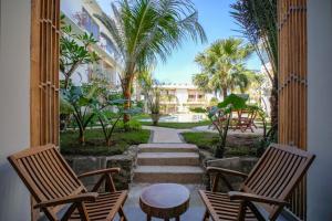 two chairs and a table on a porch with palm trees at Giri Rose Boutique Hotel in Kuta Lombok