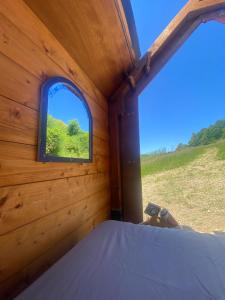 a bedroom with a window in a wooden house at Altaluna tiny house sotto le stelle in Trebbiantico +3 photos