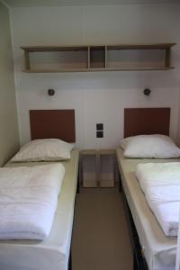 two beds in a dorm room with white sheets at Mini-chalet - Vakantiepark 't Urkerbos in Urk +8 photos