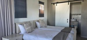 a bedroom with a bed with white sheets and pillows at Mooring Manor Chalet in Vaal Marina