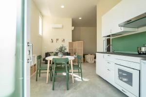 a kitchen with a table and some green chairs at Casa del Falegname - Loft Abete con cucina in San Giovanni in Bosco +8 photos