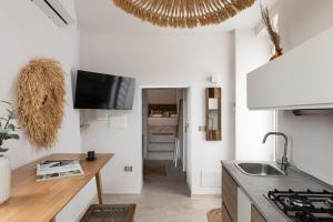 a kitchen with white walls and a sink and a tv at Begani63 Boutique Apartments in Gaeta