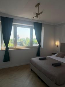 a bedroom with a bed and two large windows at Brickller Apartments by Letrent in Żyrardów