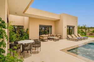 a patio with a table and chairs and a pool at Villa Gaspard - Piscine et jardin Privée Sans vis-à-vis Wifi HD in Marrakesh