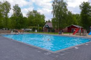 ein großes blaues Schwimmbecken mit Spielplatz und Rutsche in der Unterkunft Vakantiepark 't Urkerbos -Tiny house in Urk