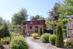ein winziges Haus in einem Garten mit einer Kiesauffahrt in der Unterkunft Vakantiepark 't Urkerbos -Tiny house in Urk
