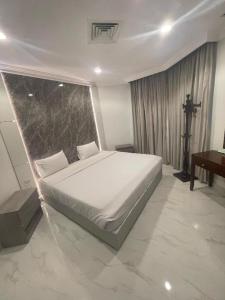 a bedroom with a white bed and a table at Continental Hotel & Suite in Kuwait