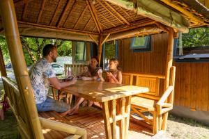 a group of people sitting at a table in a gazebo at Camping la Plage Lot Vallée de la Dordogne Rocamadour in Meyronne