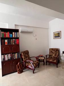 a living room with two chairs and a book shelf at Casa Tolentino in Bissau
