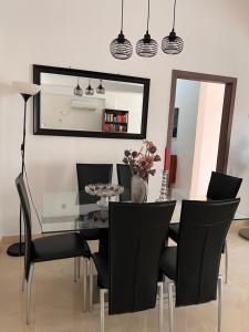 a dining room with a glass table and black chairs at Casa Tolentino in Bissau