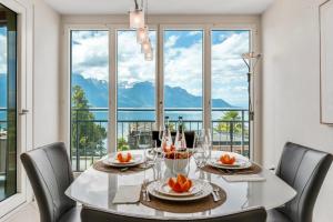 a dining room with a table with chairs and a large window at Spacious 3BR Lakeview Apartment with Terrace by GuestLee in Montreux