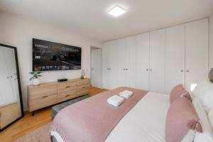 a bedroom with a large bed and a flat screen tv at Spacious 3BR Lakeview Apartment with Terrace by GuestLee in Montreux +14 photos