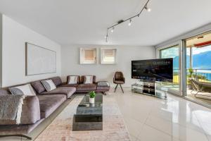 a living room with a large couch and a tv at Spacious 3BR Lakeview Apartment with Terrace by GuestLee in Montreux