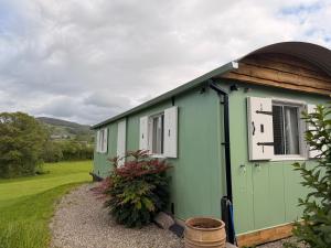 a green building with a clock on the side of it at Cwt Ieir in Ruthin