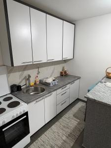a kitchen with white cabinets and a sink at FocaLux in Foča