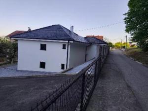 a white building with a fence next to a road at Apartman Florida ranč in Doboj