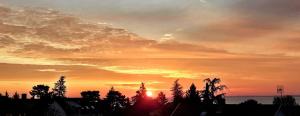 a sunset over a city with trees and the ocean at Blackbird Apartment in Balatonfüred