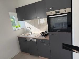 a kitchen with black cabinets and a sink and a tv at Stillvolle Apartment NV in Neukirchen-Vluyn