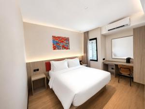 a hotel room with a white bed and a desk at SHANKEE Hotel Melawai Blok M Jakarta in Jakarta