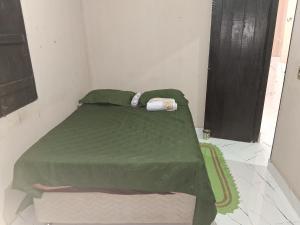 a bed with a green comforter in a room at Casa próximo a praia in Salvaterra