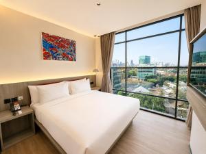 a hotel room with a bed and a large window at SHANKEE Hotel Melawai Blok M Jakarta in Jakarta