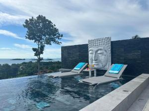 a pool with two lounge chairs and a head on the wall at Villa Bardi - Breathtaking Sea View in Plai Laem