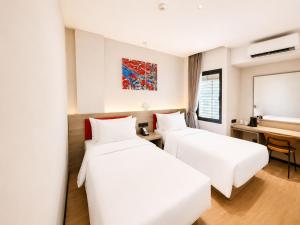 a hotel room with two beds and a desk at SHANKEE Hotel Melawai Blok M Jakarta in Jakarta