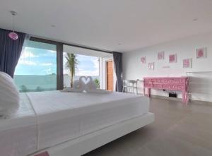 a white bedroom with a large bed and a pink desk at Villa Bardi - Breathtaking Sea View in Plai Laem +60 photos