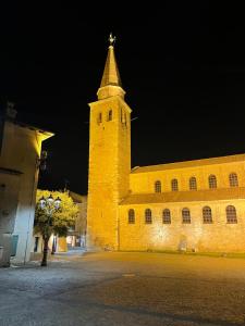 a large yellow building with a tower at night at Calle del Palazzo 12 in Grado +1 photo