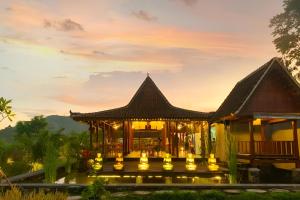a building with lights in front of a sunset at Anandinii Resort Sidemen by AGATA in Sidemen