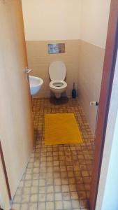 a bathroom with a toilet and a yellow rug at Ferienwohnung Am Hummerstein in Ebermannstadt +3 photos