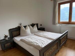 a bedroom with a bed with white sheets and a window at Ferienhaus Riedberg in Ried im Zillertal