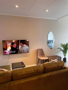 a living room with a couch and a tv on the wall at East Apartment in Egilsstaðir