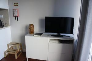 TV en la parte superior de una cómoda blanca con TV en Apartamento Monte Estoril, en Cascais