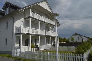 a white house with a white fence and a street light at Ferienwohnung Gesine 2 in Nienhagen +18 photos