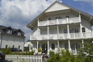 a white house with a white fence in front of it at Ferienwohnung Gesine 2 in Nienhagen