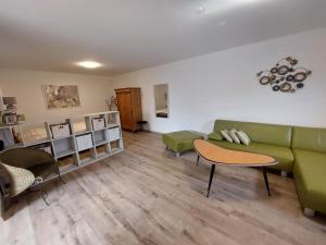 a living room with a green couch and a table at Ferienwohnung Gartenweg in Strullendorf