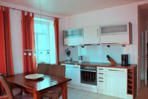 a kitchen with white cabinets and a table and a table and a dining room at Ferienwohnung in der Villa Seestern in Nienhagen